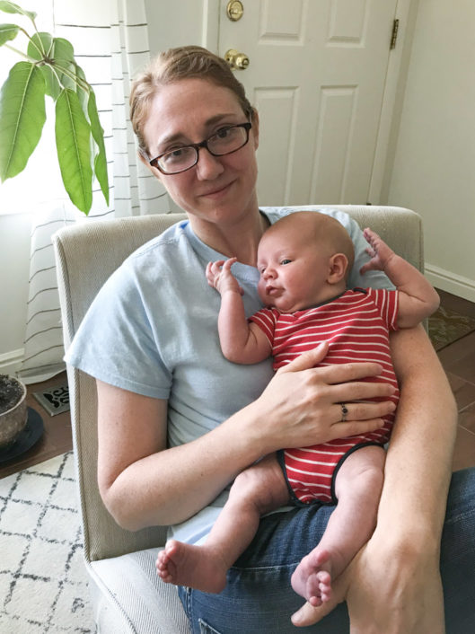 Dr. Rosemary Demos, a Literature professor at McLean, holding a baby while sitting in a chair